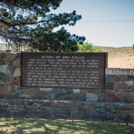 A wood monument depicting the history of Dry Falls sites on a rock foundation. 