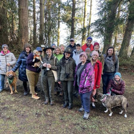 Park rangers surrounded by group of bundled up hikers standing in front of fir trees