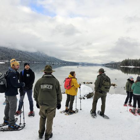 First Day Hike Snowshoers standing on snow near the edge of Lake Wennatchee looking out over the still water