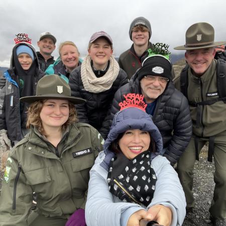 Smiling group of people with warm hats and jacket posing with Park Rangers