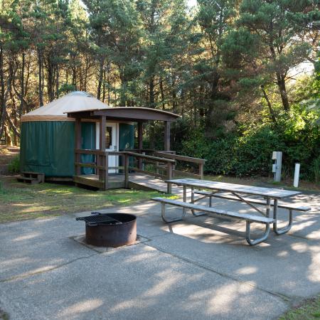 Yurt with picnic table and fire pit on concrete slab.