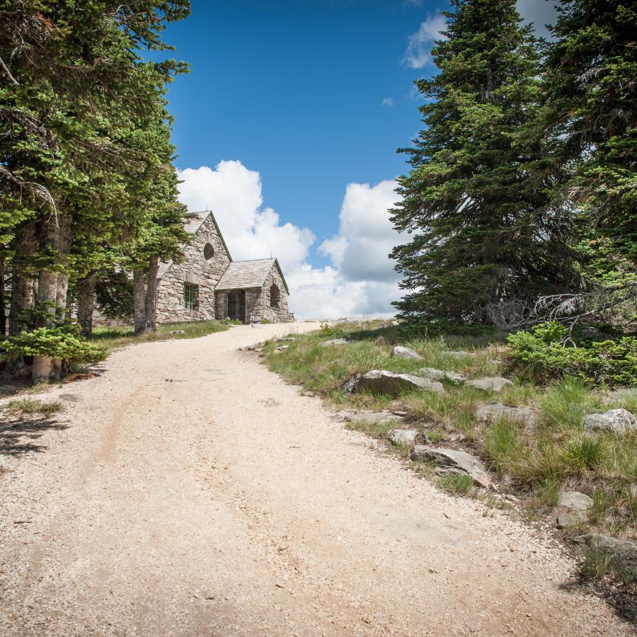 The stone Vista House is shown at the end of a gravel trail lined with trees.