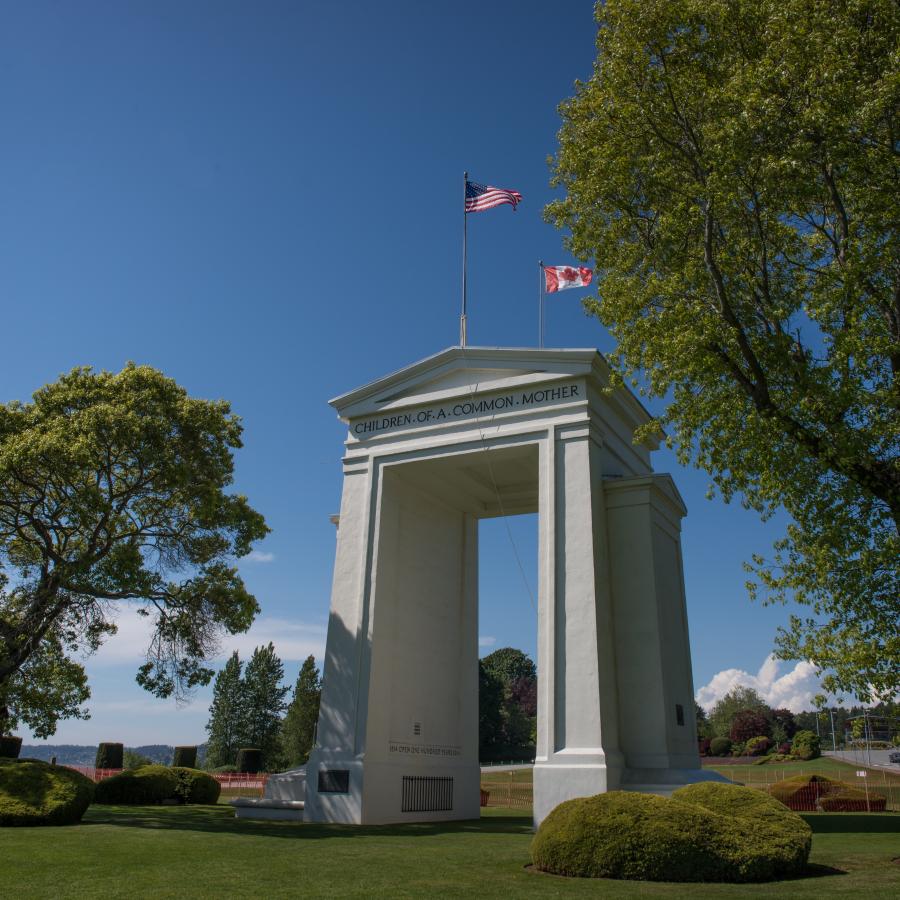 Looking at the arch on a sunny blue sky day with surrounding trees and manicured landscape