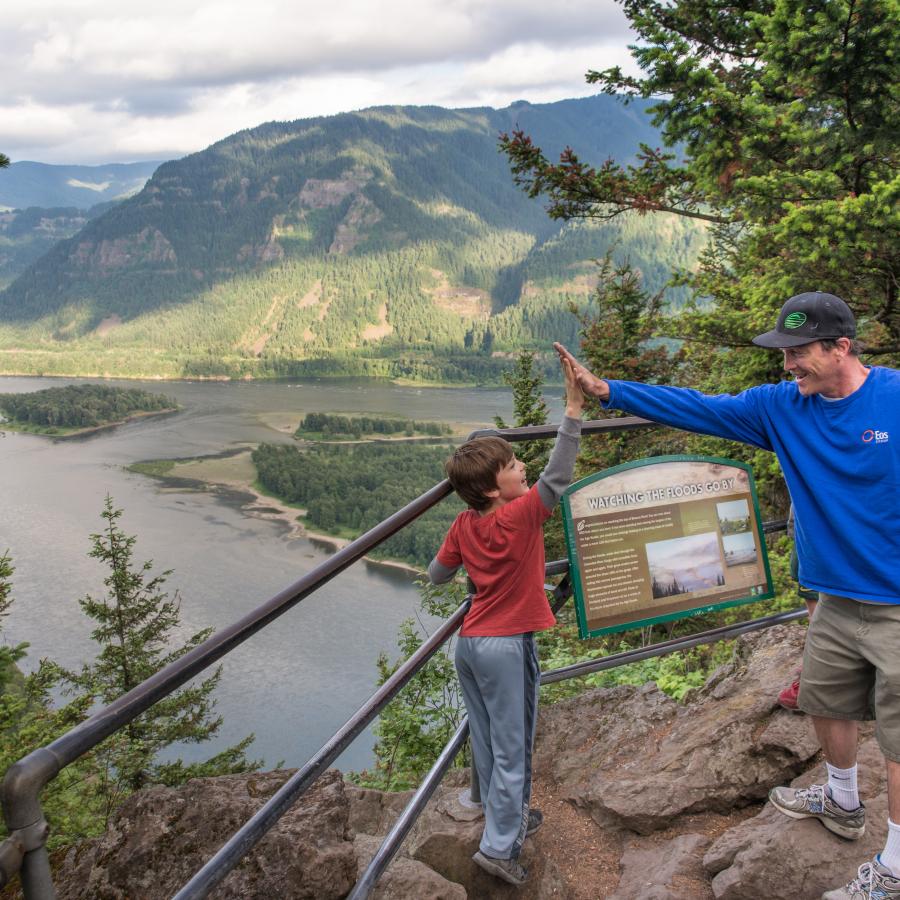 Two hikers high fiving at the overlook on Beacon Rock.