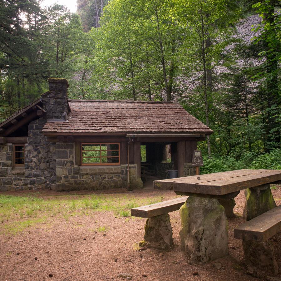 A picnic shelter  and a bench surrounded by trees at Beacon Rock State Park.