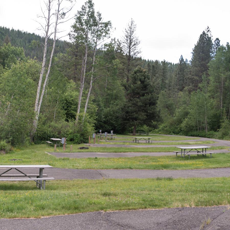 Paved RV campsite with electricity pedestal on semi-level ground surrounded by grass