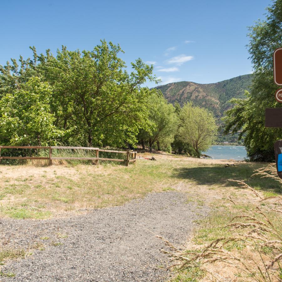 Beach path with signage showing dog on leash and pickup after your pet