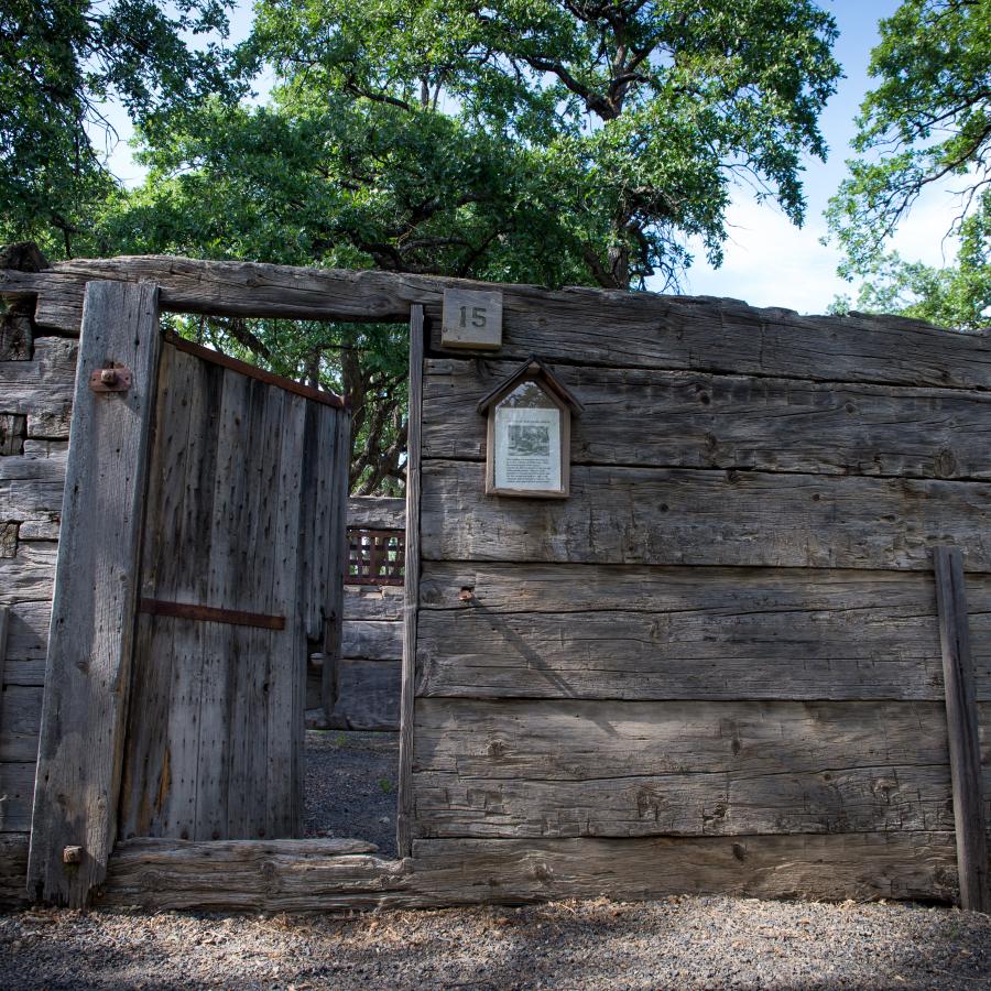 Historic wood structure surrounded by trees with some blue sky poking through the trees