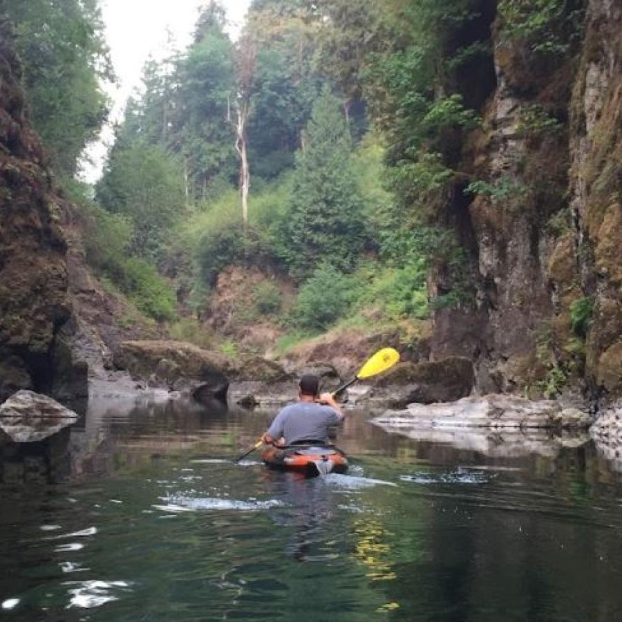 Kayaker on smooth clear lake water entering a cove