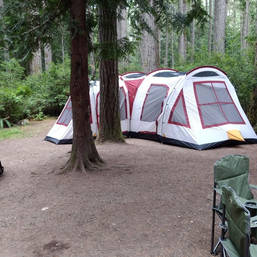 primitive campsite pitched tent and chairs surrounding campfire