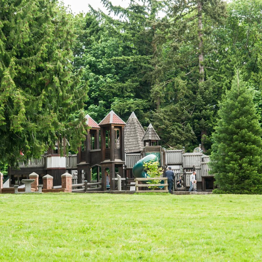 A large, wooden playground with climbing, swings, slides, and multiple levels of play.