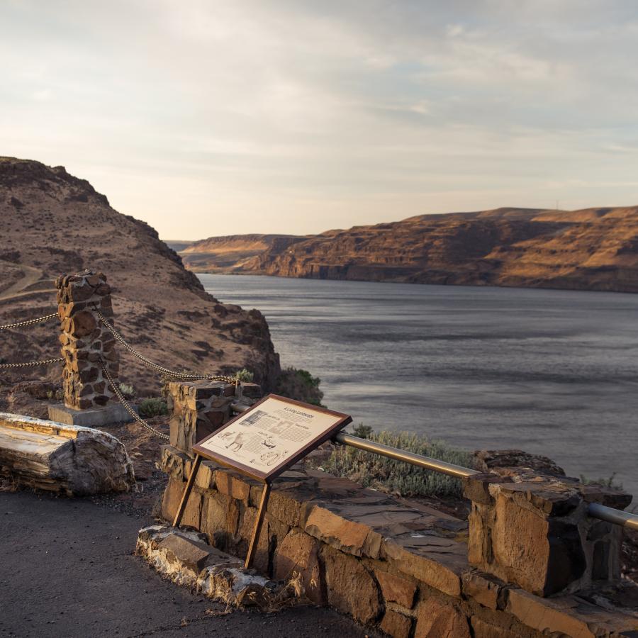 Interpretive displays overlooking Wanapum Lake. Sunset lit cliffs acoss the lake with cloudy blue sky.