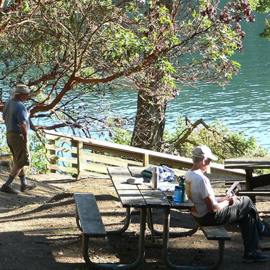 picnic table with person sitting and pathway leading to the water