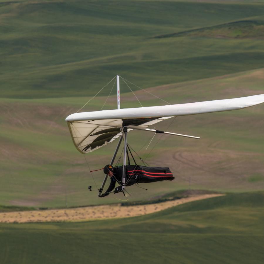 Hang gliding over grassy fields.
