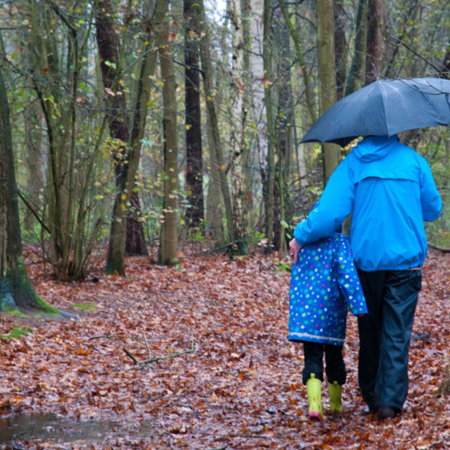 Adult and kid walking along path in the rain