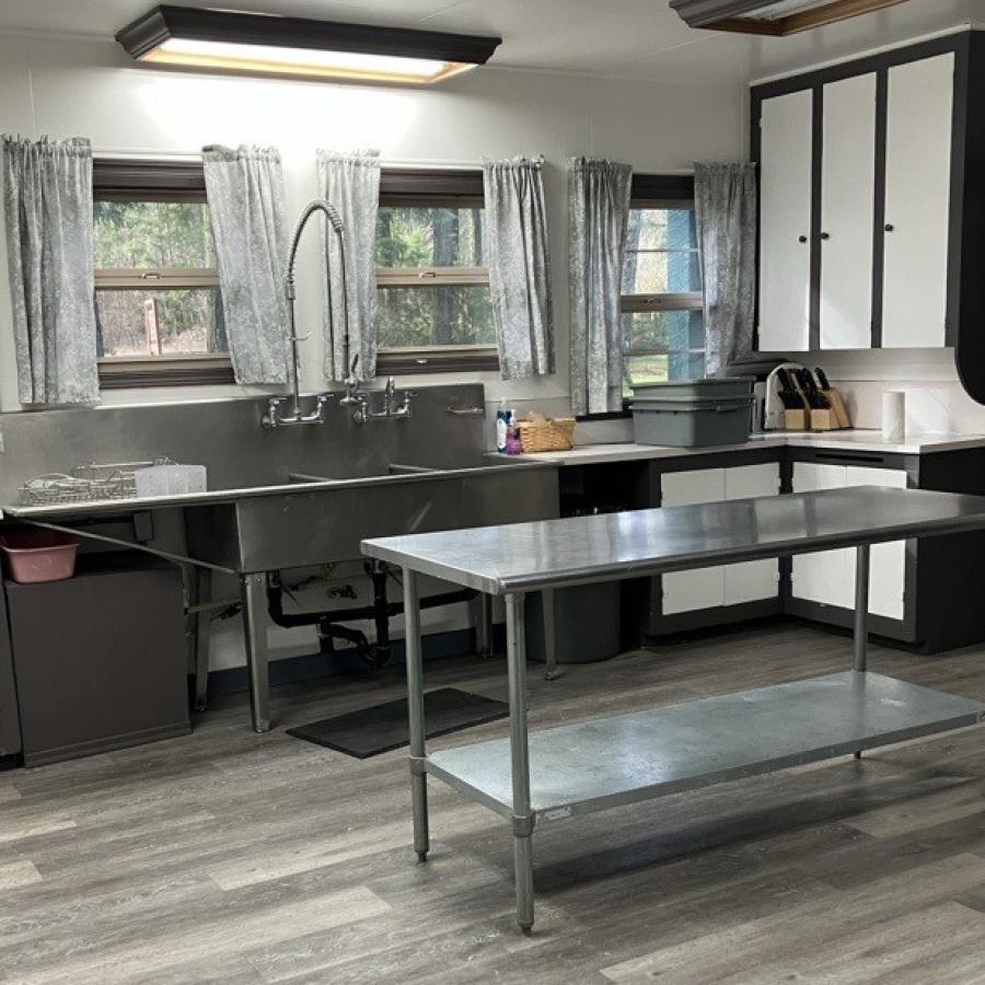 kitchen showing large industrial stainless-steel sink with stainless-steel prep table