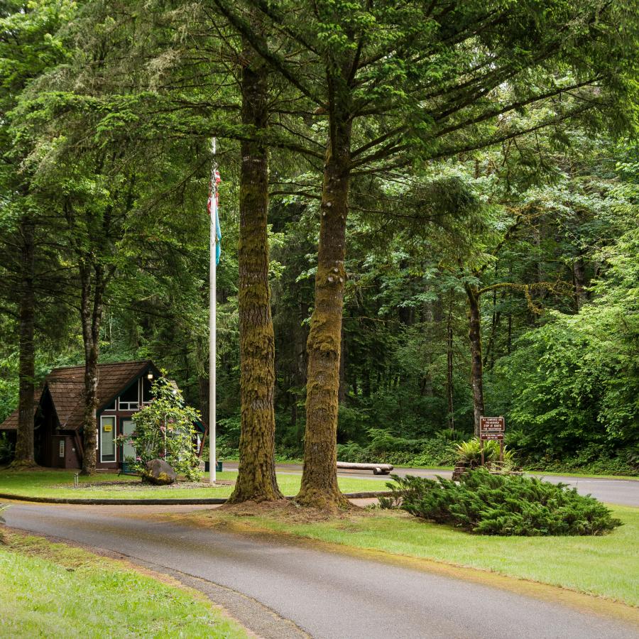 Entrance to Ike Kinswa with welcome station, surrounded by tall trees and blooming flowers.