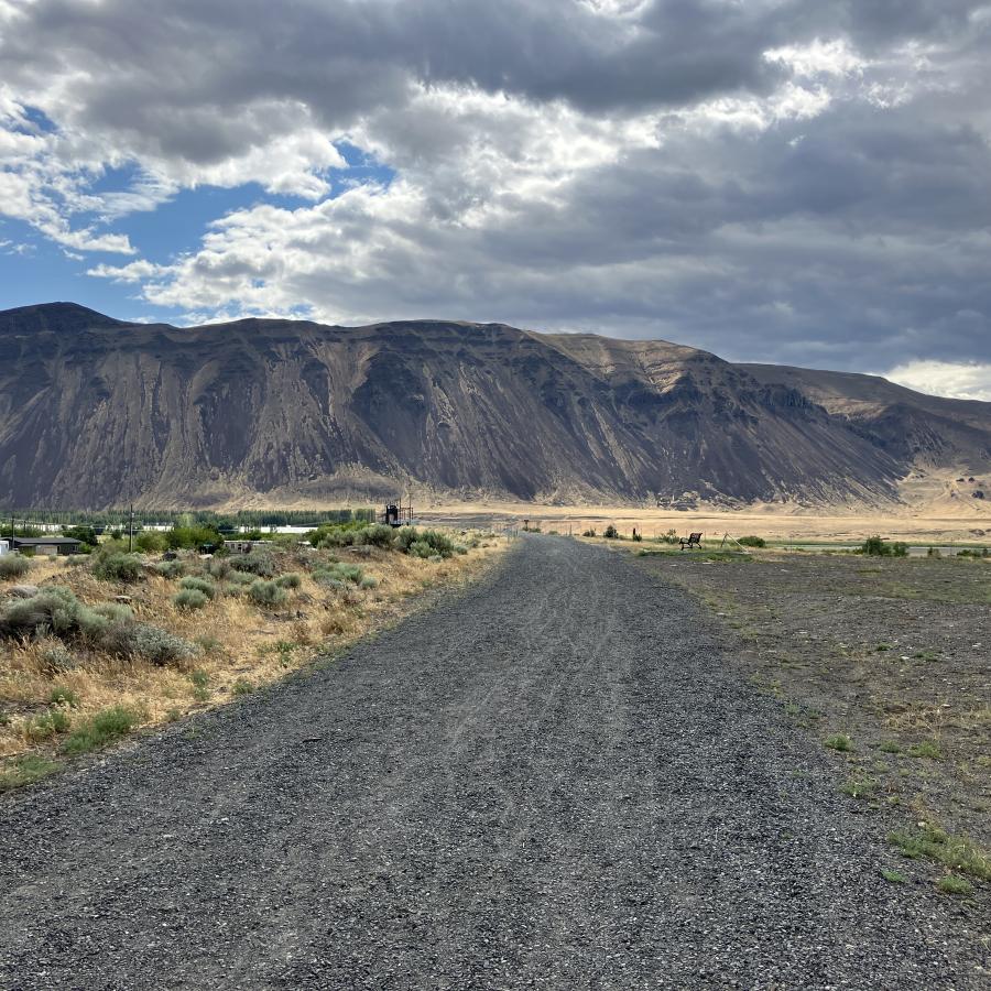 A gravel trail heads toward a scrubby mountain.