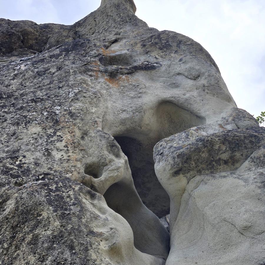 A lumpy sandstone rock formation witha sunny sky in the background