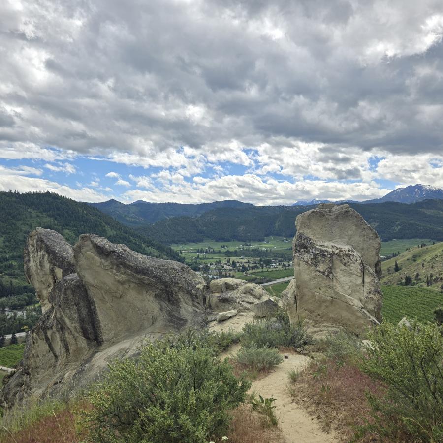 Large sandstone rocks along a trail with a sweeping view of a green valley below