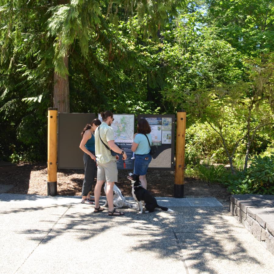 Mount St Helens Visitor Center two women, a man, and two dogs stop to look at the area map on kiosk