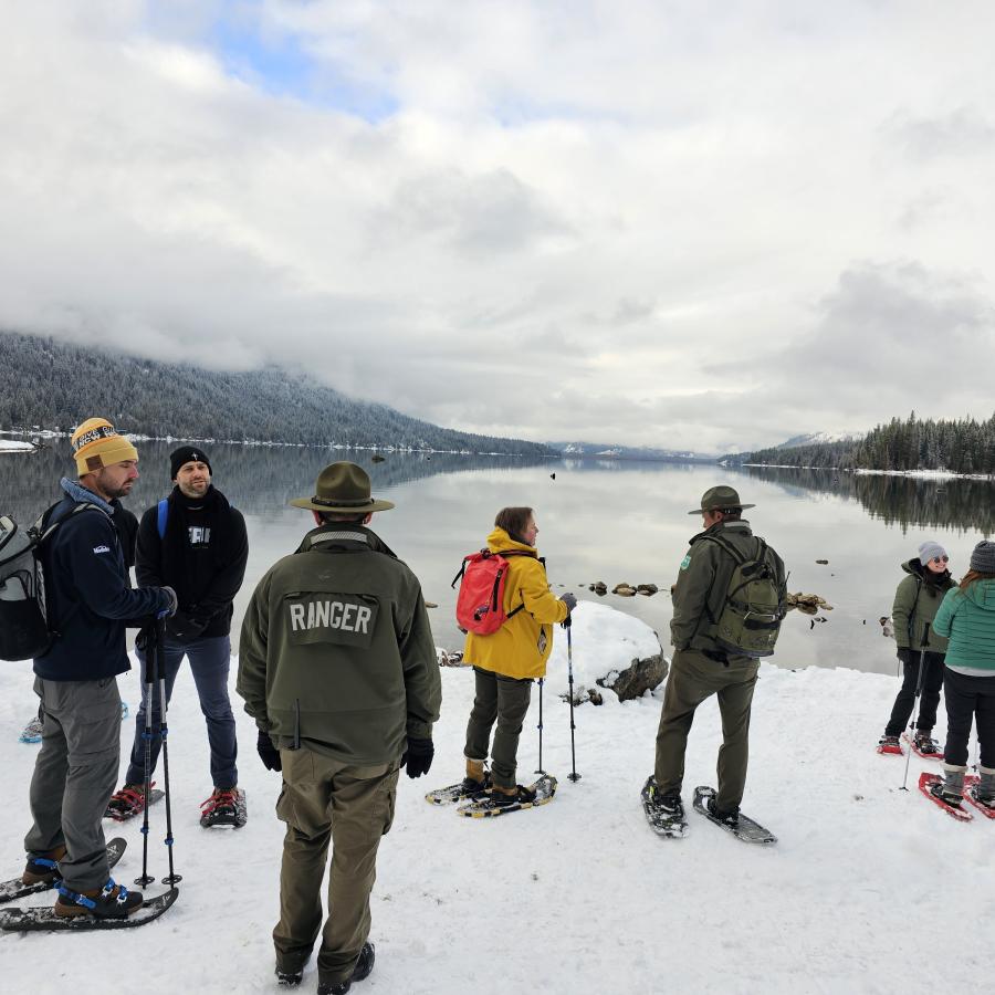 First Day Hike Snowshoers standing on snow near the edge of Lake Wennatchee looking out over the still water
