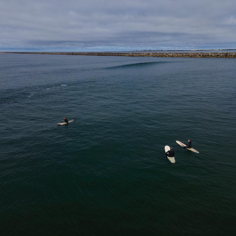 Three surfers sitting on surf boards waiting to catch the next big wave. 