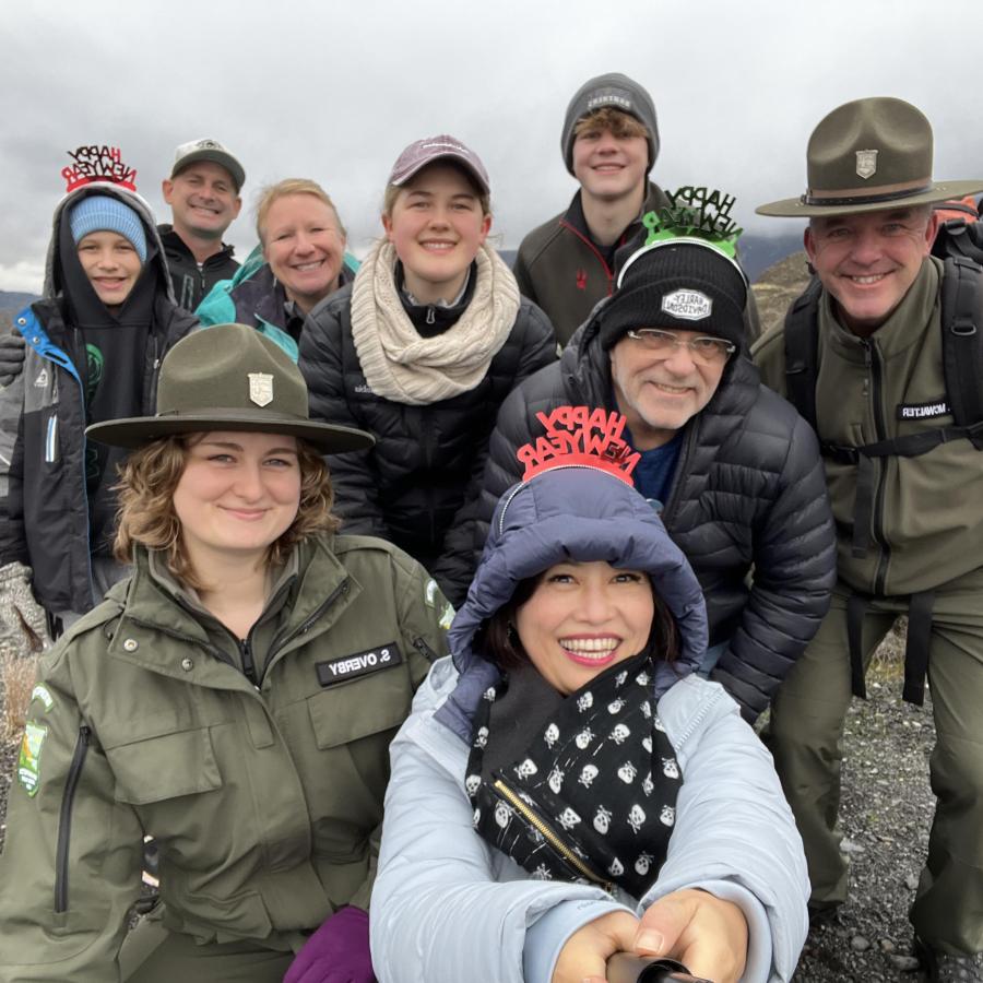 Smiling group of people with warm hats and jacket posing with Park Rangers