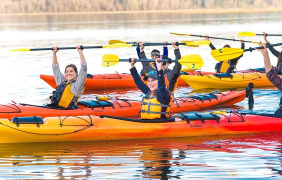 Group of kayakers with paddles held high