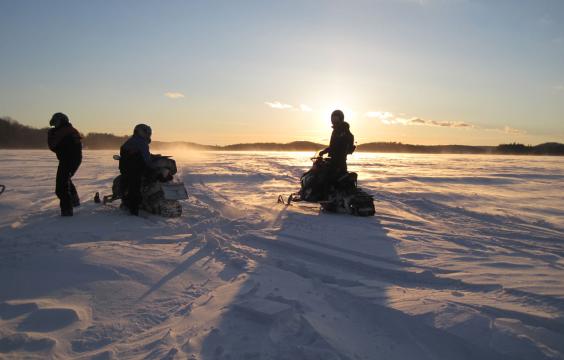 3 snowmobiles at sunset