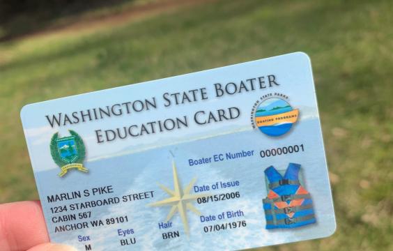 a hand holding up a mandatory boater education card with placeholder information