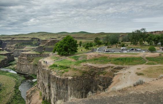 A parking lot with a short trail to an overlook at the edge of a canyon. A river is flowing below.